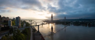 Aerial Panoramic view of Fraser River and Bridges during a vibrant sunrise. Taken in New Westminster, Greater Vancouver, British Columbia, Canada. clipart