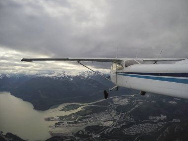 Bulutlu bir gece boyunca güzel Kanada dağ peyzaj üzerinde uçan uçak. Vancouver, British Columbia, Kanada kuzeyindeki alınan.