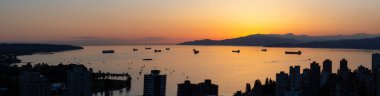 Artistic Aerial Panoramic View of a beautiful and colorful sunset over the dark city with mountains in the background. Taken in Downtown Vancouver, BC, Canada. clipart