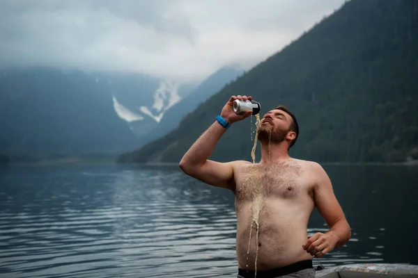 Man pouring beer from a can on himself during a party in the nature. Taken in Jones Lake, East of Vancouver, BC, Canada.