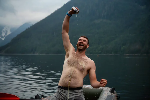 Man pouring beer from a can on himself during a party in the nature. Taken in Jones Lake, East of Vancouver, BC, Canada.