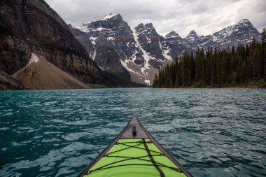 Kayaking in Glacier Water surounded by the beautiful Canadian Rocky Mountains. Taken in Moraine Lake, Banff National Park, Alberta, Canada. clipart
