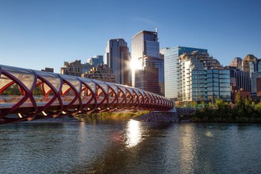 Peace Bridge across Bow River during a vibrant summer sunrise. Taken in Calgary, Alberta, Canada. clipart