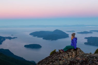 Bir dağ uçurumun tepesinde maceracı kadın güzel yaz güneşin tadını çıkarıyor. Mount Brunswick, aslanlar Bay, Vancouver, Bc, Kanada kuzeyindeki üzerinde gerçekleştirilen.
