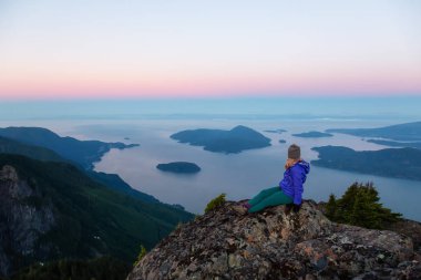 Bir dağ uçurumun tepesinde maceracı kadın güzel yaz güneşin tadını çıkarıyor. Mount Brunswick, aslanlar Bay, Vancouver, Bc, Kanada kuzeyindeki üzerinde gerçekleştirilen.