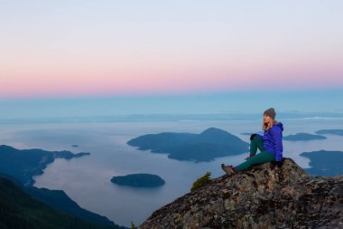 Bir dağ uçurumun tepesinde maceracı kadın güzel yaz güneşin tadını çıkarıyor. Mount Brunswick, aslanlar Bay, Vancouver, Bc, Kanada kuzeyindeki üzerinde gerçekleştirilen.