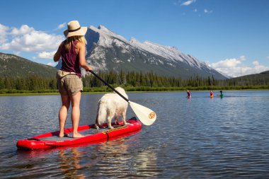 Banff, Alberta, Kanada - 19 Haziran 2018: Maceracı kadın köpeğini ile bir yandan çarklı gemide güzel güneşli yaz gün gölde keyif alıyor.