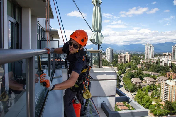 stock image Burnaby, Vancouver, British Columbia, Canada - July 06, 2018: High rise rope access window cleaner is working during a hot sunny summer day.