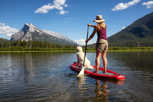 Banff, Alberta, Kanada - 19 Haziran 2018: Maceracı kadın köpeğini ile bir yandan çarklı gemide güzel güneşli yaz gün gölde keyif alıyor.