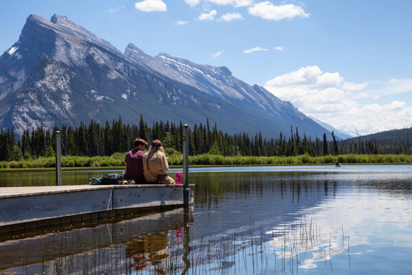 Banff, Alberta, Canada - June 19, 2018:  Couple friends are enjoying the beautiful view on a wooden dock.