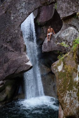 Squamish, British Columbia, Kanada - 29 Temmuz 2018: Maceracı adam Monmouth kanyonunda bir uçurumun üstünde oturuyor.