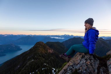 Bir dağ uçurumun tepesinde maceracı kadın güzel yaz güneşin tadını çıkarıyor. Mount Brunswick, aslanlar Bay, Vancouver, Bc, Kanada kuzeyindeki üzerinde gerçekleştirilen.