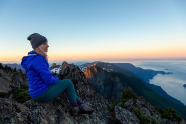 Bir dağ uçurumun tepesinde maceracı kadın güzel yaz güneşin tadını çıkarıyor. Mount Brunswick, aslanlar Bay, Vancouver, Bc, Kanada kuzeyindeki üzerinde gerçekleştirilen.