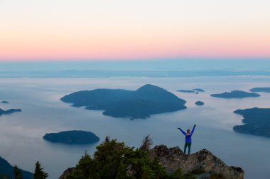 Bir dağ uçurumun tepesinde maceracı kadın güzel yaz güneşin tadını çıkarıyor. Mount Brunswick, aslanlar Bay, Vancouver, Bc, Kanada kuzeyindeki üzerinde gerçekleştirilen.