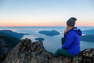 Bir dağ uçurumun tepesinde maceracı kadın güzel yaz güneşin tadını çıkarıyor. Mount Brunswick, aslanlar Bay, Vancouver, Bc, Kanada kuzeyindeki üzerinde gerçekleştirilen.