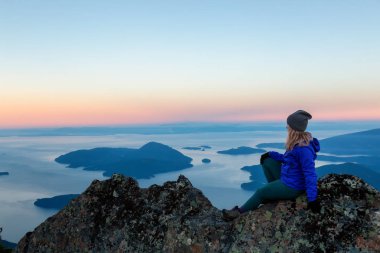 Bir dağ uçurumun tepesinde maceracı kadın güzel yaz güneşin tadını çıkarıyor. Mount Brunswick, aslanlar Bay, Vancouver, Bc, Kanada kuzeyindeki üzerinde gerçekleştirilen.
