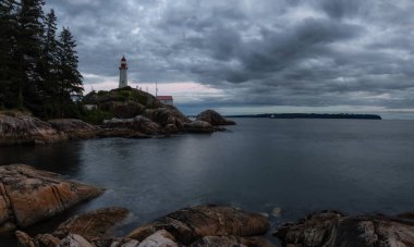 Canlı bir bulutlu gün batımı sırasında kayalık bir kıyısında deniz feneri. Horseshoe Bay, Batı Vancouver, British Columbia, Kanada alınan.