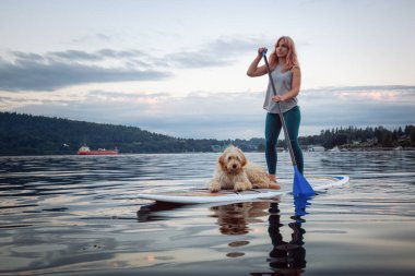 Canlı bir yaz günbatımında köpekli bir kız. Deep Cove 'da çekildi, Kuzey Vancouver, BC, Kanada.
