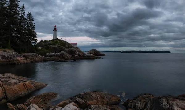 Canlı bir bulutlu gün batımı sırasında kayalık bir kıyısında deniz feneri. Horseshoe Bay, Batı Vancouver, British Columbia, Kanada alınan.