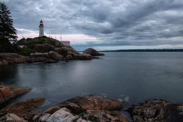 Canlı bir bulutlu gün batımı sırasında kayalık bir kıyısında deniz feneri. Horseshoe Bay, Batı Vancouver, British Columbia, Kanada alınan.