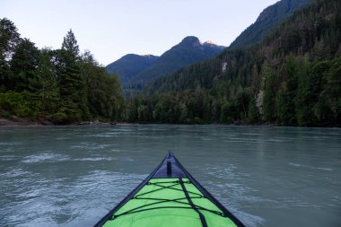 Bir canlı yaz gün batımı sırasında Kanada dağlarla çevrili bir nehir kanosu. Squamish, British Columbia, Kanada alınan.