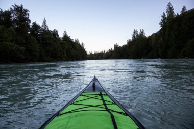 Bir canlı yaz gün batımı sırasında Kanada dağlarla çevrili bir nehir kanosu. Squamish, British Columbia, Kanada alınan.