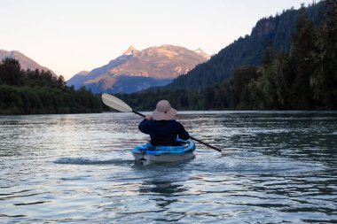 Bir canlı yaz gün batımı sırasında Kanada dağlarla çevrili bir nehir kanosu. Squamish, British Columbia, Kanada alınan.