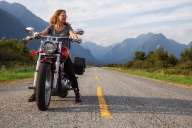Kadın Kanada dağlarla çevrili doğal bir yol üzerinde bir motosiklet Binme. Pitt Meadows, büyük Vancouver, Bc, Kanada alınan.