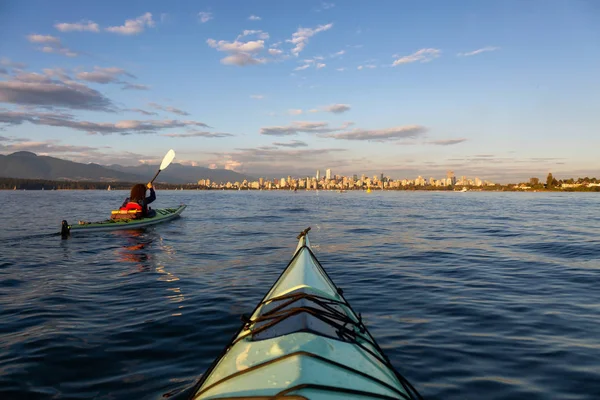 Sea Kayaking in front of Downtown City during a vibrant sunny summer sunset. Taken in Vancouver, BC, Canada.