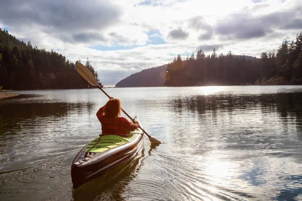 Girl kayaking in a river near the Pacific Ocean during a cloudy summer evening. Taken in San Josef Bay, Cape Scott, Northern Vancouver Island, BC, Canada.