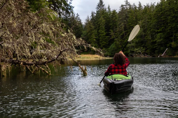 Girl kayaking in a river during a cloudy summer day. Taken in Cape Scott Provincial Park, Northern Vancouver Island, BC, Canada.