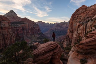 Bir uçurumun kenarında, maceracı kız güzel manzaralı Kanyon canlı bir gün batımı sırasında bakıyor. Zion National Park, Utah, Amerika Birleşik Devletleri'nde çekilen.