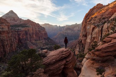 Bir uçurumun kenarında, maceracı kız güzel manzaralı Kanyon canlı bir gün batımı sırasında bakıyor. Zion National Park, Utah, Amerika Birleşik Devletleri'nde çekilen.