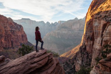 Bir uçurumun kenarında, maceracı kız güzel manzaralı Kanyon canlı bir gün batımı sırasında bakıyor. Zion National Park, Utah, Amerika Birleşik Devletleri'nde çekilen.