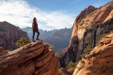 Bir uçurumun kenarında, maceracı kız güzel manzaralı Kanyon canlı bir gün batımı sırasında bakıyor. Zion National Park, Utah, Amerika Birleşik Devletleri'nde çekilen.