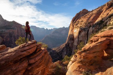 Bir uçurumun kenarında, maceracı kız güzel manzaralı Kanyon canlı bir gün batımı sırasında bakıyor. Zion National Park, Utah, Amerika Birleşik Devletleri'nde çekilen.