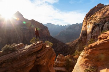Bir uçurumun kenarında, maceracı kız güzel manzaralı Kanyon canlı bir gün batımı sırasında bakıyor. Zion National Park, Utah, Amerika Birleşik Devletleri'nde çekilen.