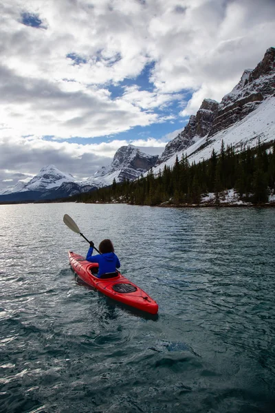 Bir bulutlu sabah sırasında Kanada Rocky Dağları ile çevrili bir buzul Gölü'kayak maceracı kız. Alınan yay Gölü, Banff, İngiltere.