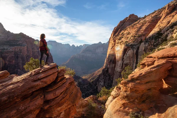 Bir uçurumun kenarında, maceracı kız güzel manzaralı Kanyon canlı bir gün batımı sırasında bakıyor. Zion National Park, Utah, Amerika Birleşik Devletleri'nde çekilen.