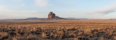 Bir kuru çöl dağ tepe canlı bulutlu gün doğumu sırasında arka planda ile dramatik panoramik manzara görünümü. Shiprock, New Mexico, Amerika Birleşik Devletleri, alınan.