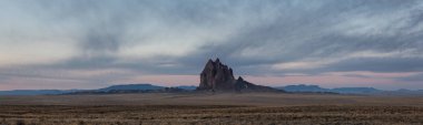 Bir kuru çöl dağ tepe canlı bulutlu gün doğumu sırasında arka planda ile dramatik panoramik manzara görünümü. Shiprock, New Mexico, Amerika Birleşik Devletleri, alınan.