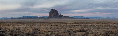 Bir kuru çöl dağ tepe canlı bulutlu gün doğumu sırasında arka planda ile dramatik panoramik manzara görünümü. Shiprock, New Mexico, Amerika Birleşik Devletleri, alınan.