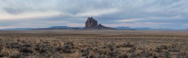 Bir kuru çöl dağ tepe canlı bulutlu gün doğumu sırasında arka planda ile dramatik panoramik manzara görünümü. Shiprock, New Mexico, Amerika Birleşik Devletleri, alınan.