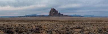 Bir kuru çöl dağ tepe canlı bulutlu gün doğumu sırasında arka planda ile dramatik panoramik manzara görünümü. Shiprock, New Mexico, Amerika Birleşik Devletleri, alınan.