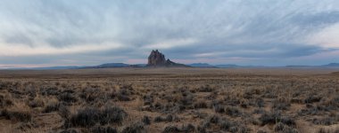 Bir kuru çöl dağ tepe canlı bulutlu gün doğumu sırasında arka planda ile dramatik panoramik manzara görünümü. Shiprock, New Mexico, Amerika Birleşik Devletleri, alınan.
