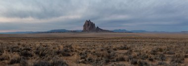 Bir kuru çöl dağ tepe canlı bulutlu gün doğumu sırasında arka planda ile dramatik panoramik manzara görünümü. Shiprock, New Mexico, Amerika Birleşik Devletleri, alınan.