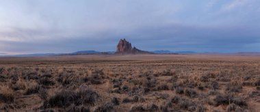Bir kuru çöl dağ tepe canlı bulutlu gün doğumu sırasında arka planda ile dramatik panoramik manzara görünümü. Shiprock, New Mexico, Amerika Birleşik Devletleri, alınan.