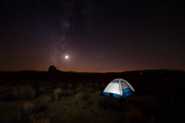 Bir gece açık gökyüzü güneş battıktan sonra sırasında arka planda bir dağ tepe ile yaktı çadır çölde. Shiprock, New Mexico, Amerika Birleşik Devletleri, alınan.