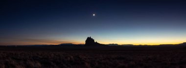 Bir gece açık gökyüzü güneş battıktan sonra sırasında arka planda bir dağ tepe ile kuru çöl dramatik panoramik manzara görünümü. Shiprock, New Mexico, Amerika Birleşik Devletleri, alınan.