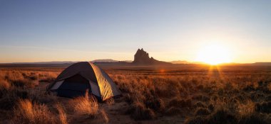 Panoramik manzaralı kuru çölde bir çadır bir dağ tepe ile canlı bir gün batımı sırasında arka planda dikkat çekici. Shiprock, New Mexico, Amerika Birleşik Devletleri, alınan.